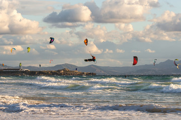 Kitesurfing in Tarifa. Plenty of colorful kites flying against a background of the mountains, beautiful clouds and waves of the Atlantic Ocean