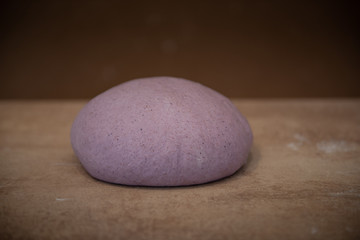 Preparation for craft bread lilac-colored dough on a brown background