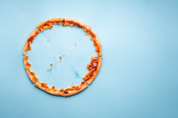 Pizza crust leftovers on blue paper background, top view