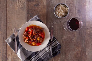 A plate with goulash or beef stew on the table. Photographed in a flat top down view.