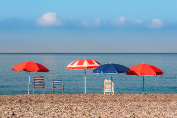 Parasols and chairs looking out to the Mediterranean sea horizon on the empty beach of La Herradura, Costa Tropical, Andalusia, Spain
