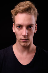 Face of young blond Scandinavian man against black background