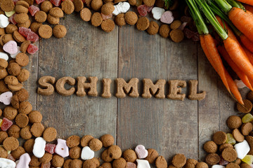 Dutch candy called Pepernoten eaten during Sinterklaas feast. Beside it carrots to be given to the horse of Sinterklaas. The candy is arranged in the Dutch word for the Grey horse of Santa Claus