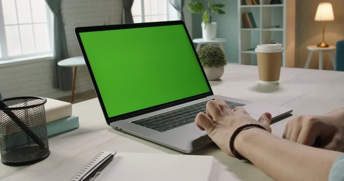 Close up shot of hands of freelancer working with chroma key green screen laptop, using trackpad scrolling through website - technology concept 4k video template