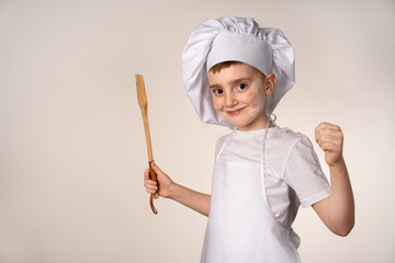A cute little boy in a chef's costume cooks food with emotions