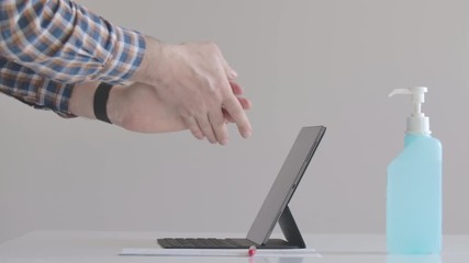 Caucasian businessman disinfecting hands and tablet before work. Side view of man using sanitizer on Covid-19 lockdown. Coronavirus quarantine, isolation, hygiene, health care. - Powered by Adobe