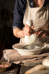 Preparation of cottage cheese - woman straining the milk through a cheesecloth