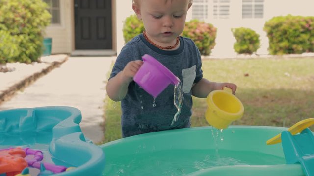 Boy pouring cup of water on water toys