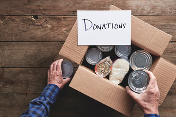 a person packing a donation box with food items