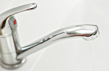 Chrome silver tap faucet with water flowing, closeup detail