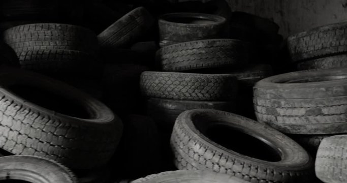 Pile of many old rubber car tires in shop of processing recycling plant. Landfill of used automobile wheel tyres. Seasonal car tire replacement. Environmental protection, recycling of used materials.