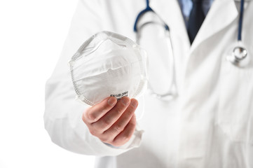 Covid-19 concept. The doctor's hands hold a protective mask, offering to patient, to protect against the coronavirus in a pandemic outbreak .