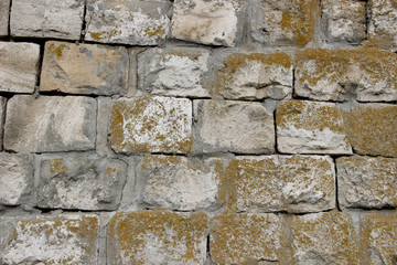 Old wall made of stone blocks covered in moss 