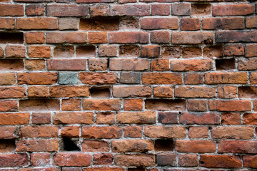 Old damaged brick wall with holes in place of some bricks