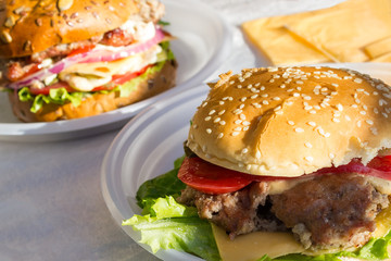 appetizing fresh homemade burger with with meat, cheese, tomato, lettuce and onion on plate. Delicious fast food concept. Copyspace