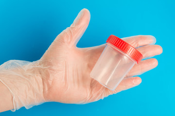 Doctor hand in medical glove holds an empty plastic container for tests