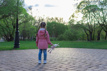little girl outdoors alone with a toy, without parents, social