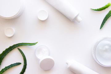 White squeeze tubes, bottles of cream with aloe vera extract flat lay on white background top view copy space. Beauty skincare, natural cosmetic, daily products. Web banner. Stock photo.