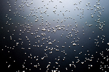 white confectionery sprinkle in the form of balls on a black background