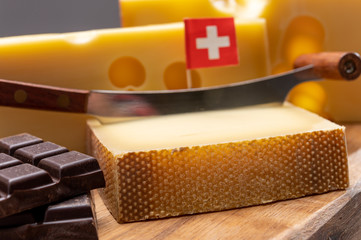 Tasty Swiss food, block of medium-hard yellow cheese emmental or emmentaler with round holes, matured gruyere and high quality milk chocolate