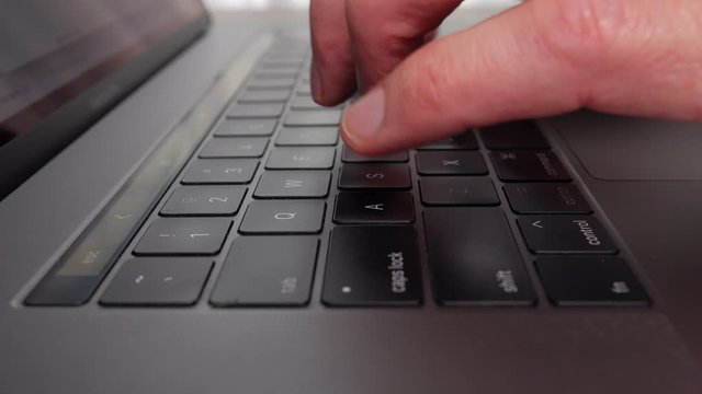 Extreme close-up of fingers typing on the keyboard of a laptop, side view