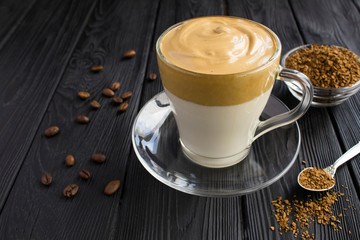 Dalgona coffee in the glass cup on  the black wooden  background. Closeup.