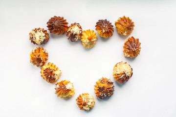 Heart made of profiteroles. Romantic food frame on a white background. Homemade baking. Dessert close-up. Sweets with whipped cream. For sweets lovers