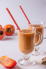Homemade smoothie of persimmon, apples, ginger and cinnamon to increase immunity in two glass on white background, vertical format, Closeup