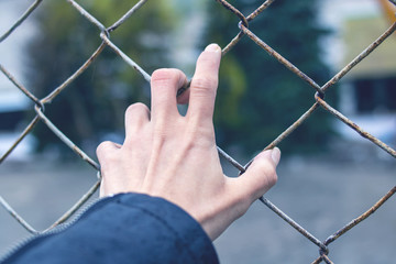 Hand on a fence net, bondage concept