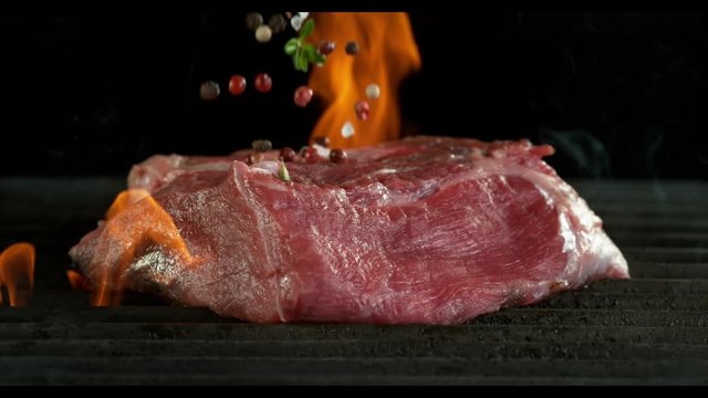 Close-up of falling raw tasty beef steak on iron cast grate, super slow motion, filmed on high speed cinematic camera at 1000 fps.