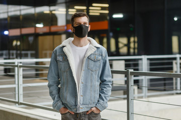 man in a black medical mask stands on an empty city street