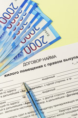 Registration and signing of the housing rent agreement. Russian text "apartment rental Agreement with the right to buy", ruble notes for payment pen