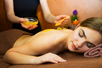 Obraz na płótnie Canvas Beautiful woman in spa salon having spa therapy honey procedure with hands of masseur