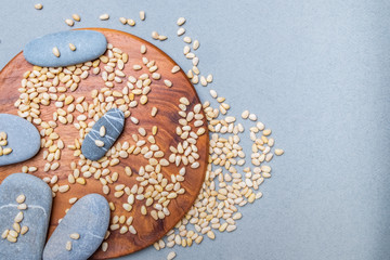 Flat lay. Oval gray stones on a wooden stand on a gray background in a placer of Siberian cedar...