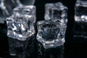 Ice cubes. Reflection of ice cubes on the black background of the table.