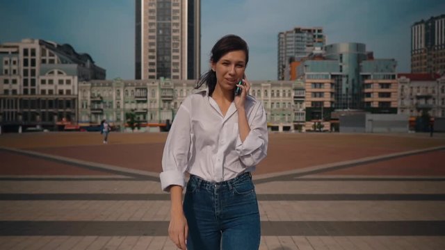 happy smiling businesswoman holding mobile talking with client by phone trendy female in city slow motion