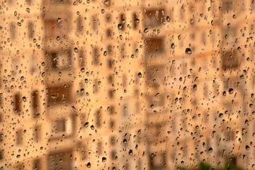 Close raindrops on the window glass against the blurred summer landscape