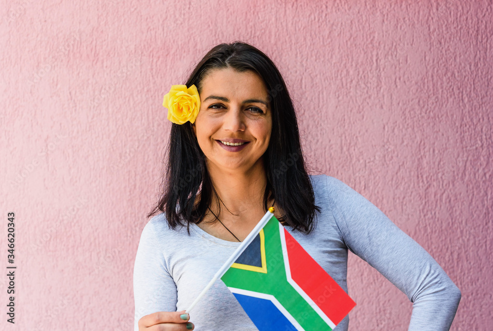 Wall mural woman holds flag of south africa in front of isolated wall background