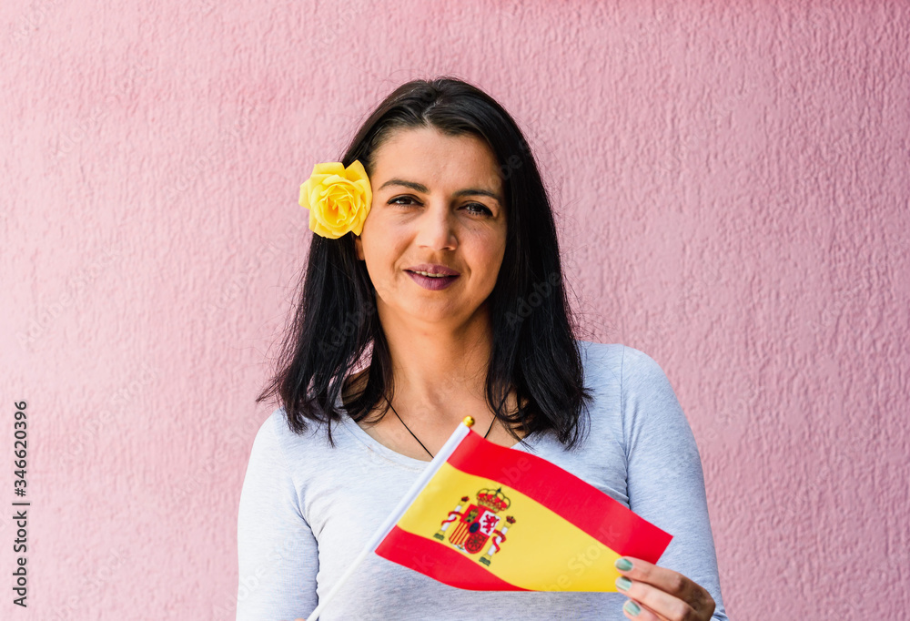 Wall mural Woman holds flag of Spain in front of isolated wall background