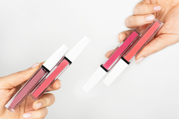 Pink lip gloss in tube template. Lipstick color swatch set. Colored closed bottles of liquid lipstick and lip gloss arranged in a row on clean white or grey background. Space for text. Beauty concept