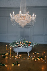 A bathroom filled with fresh flowers - roses, lilies, eucalyptus, on a gray background in a room...
