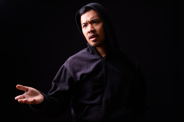 Portrait of stressed young Asian man in hoodie complaining with hand raised