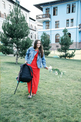 a beautiful girl walks through the Park with a backpack and smiles