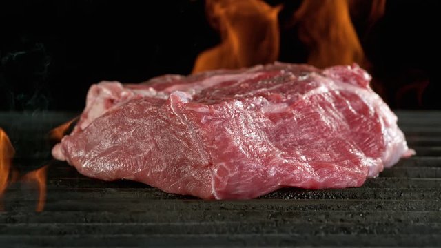 Close-up of falling raw tasty beef steak on iron cast grate, super slow motion, filmed on high speed cinematic camera at 1000 fps.