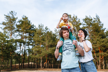 Family in nature. Dad, mom and son inflate soap balls