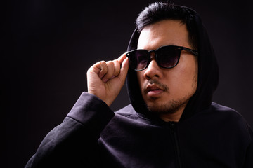 Fototapeta premium Portrait of young Asian man in hoodie wearing sunglasses