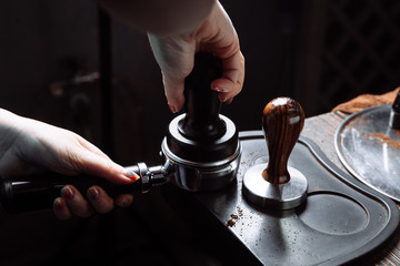 Barista pressing ground coffee into portafilter with a tamper.