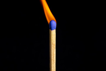 Single matchstick on fire in front of black background.