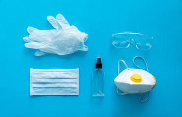 Medical protective mask, respirator ffp, rubber gloves, antiseptic and protective glasses lie on a blue background. Anti-virus protection kit against covid-19. Coronavirus pandemic 2019.