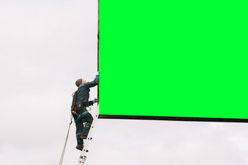 Industrial climber going up the ladder to the billboard. Risky job. Work on height. Freу space. Chromakey